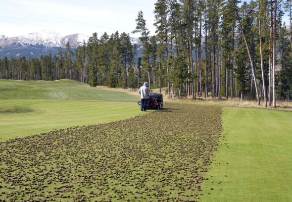 Greenkeeper pulling a Toro ProCore aerator across a recently aerated green