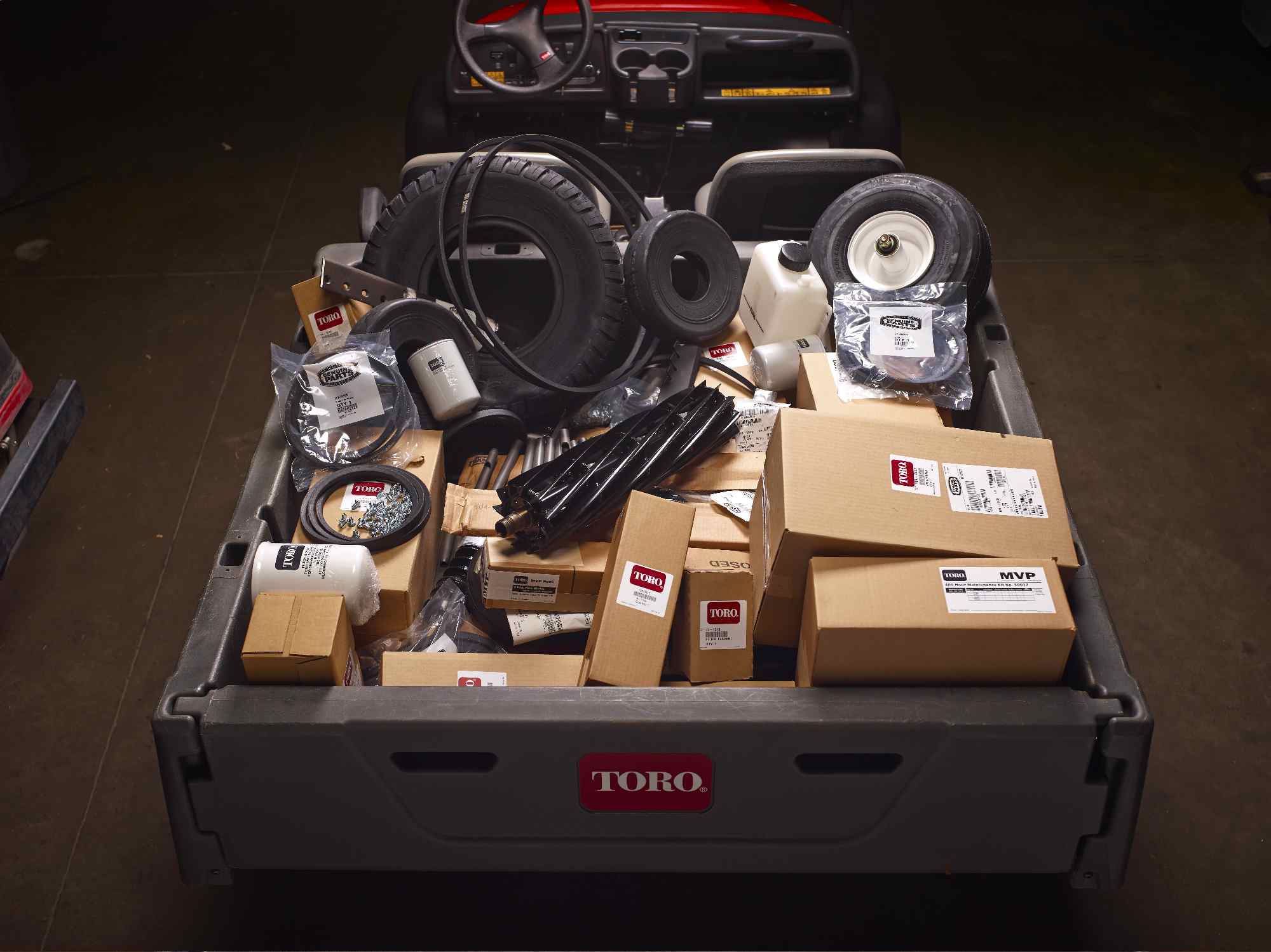 A selection of Toro parts in the bed of a Workman utility vehicle.