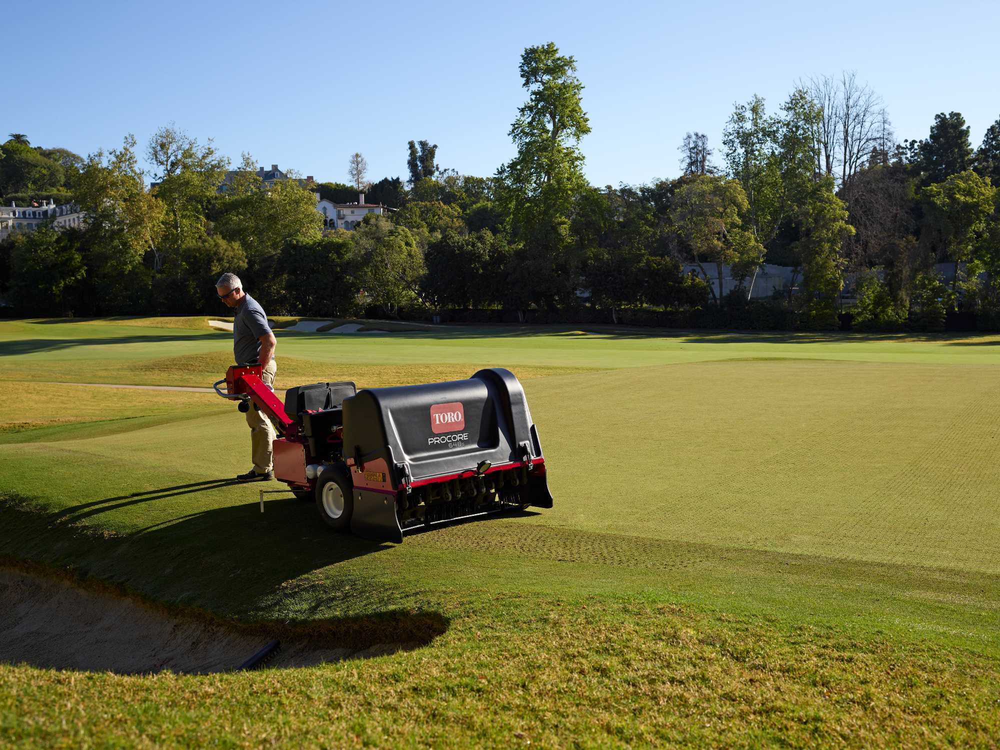 Greenkeeper using Toro ProCore aerator on golf course green to maintain healthy, high-quality turf.