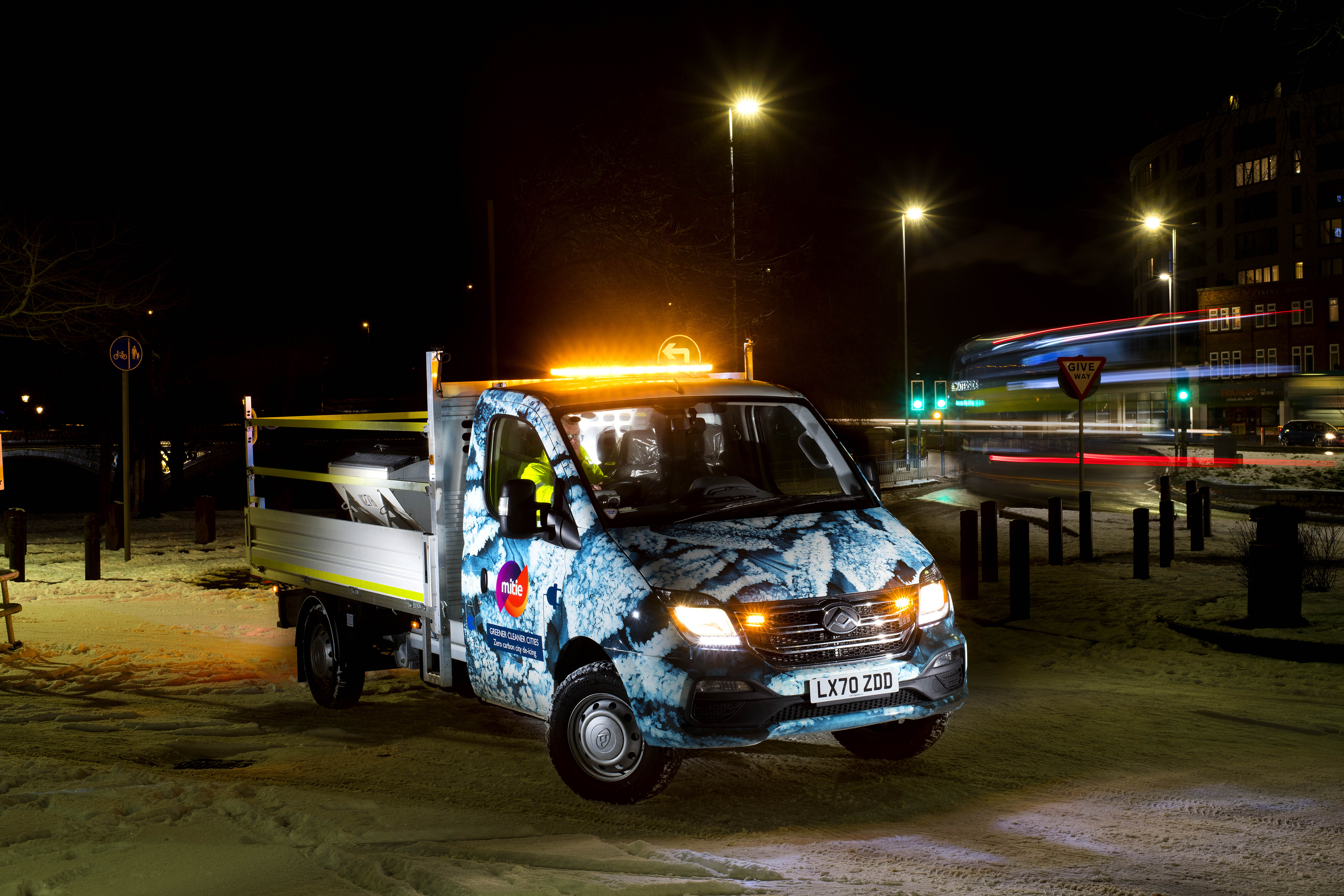 Electric Maxus truck with amber lights operating at night in snowy city streets, part of Reesink e-Vehicle sustainability fleet.