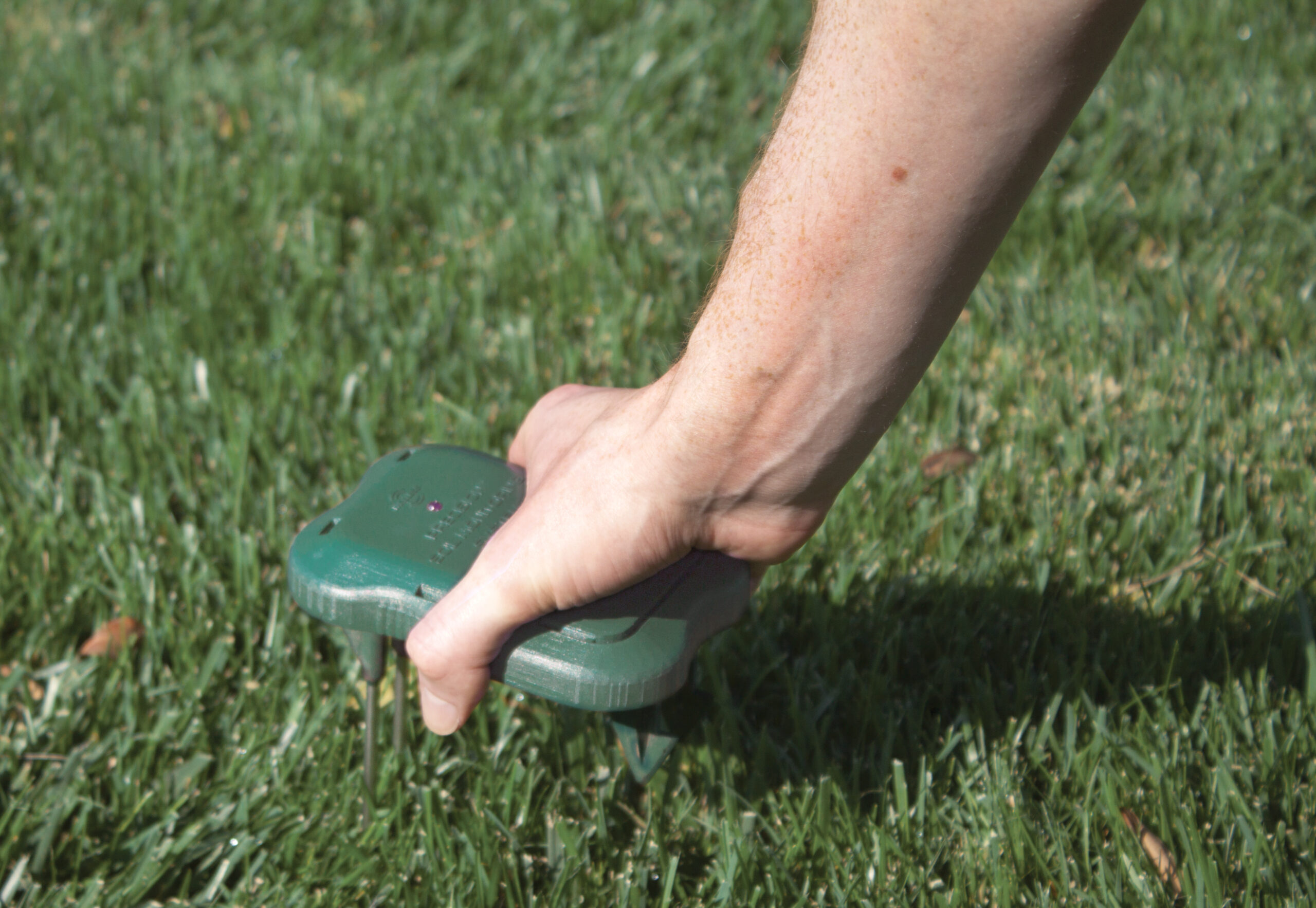 Groundskeeper checking irrigation head on turf area to ensure optimal water distribution and system performance.