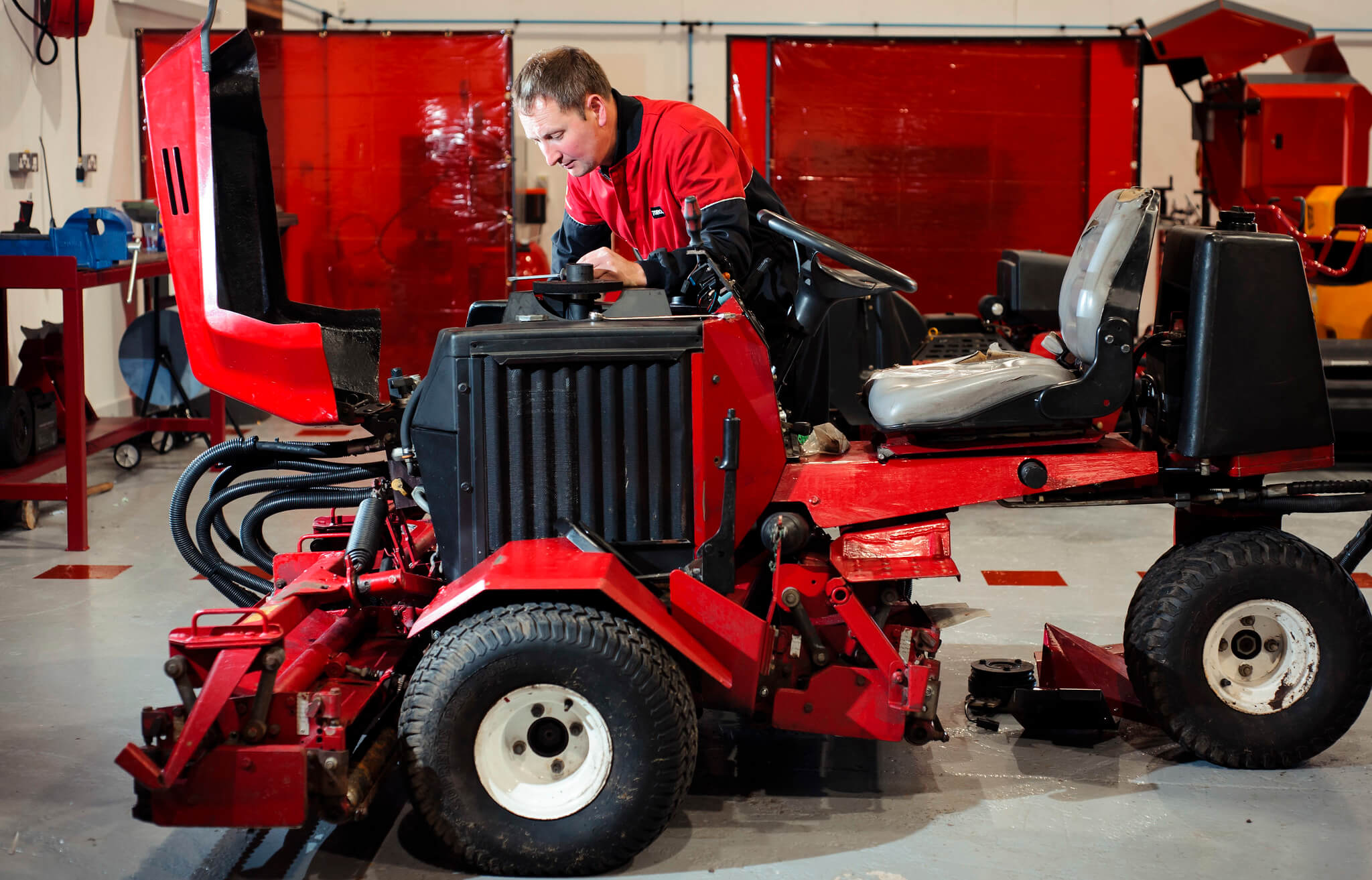 Turfcare mechanic looks down into the engine of a Toro mower.