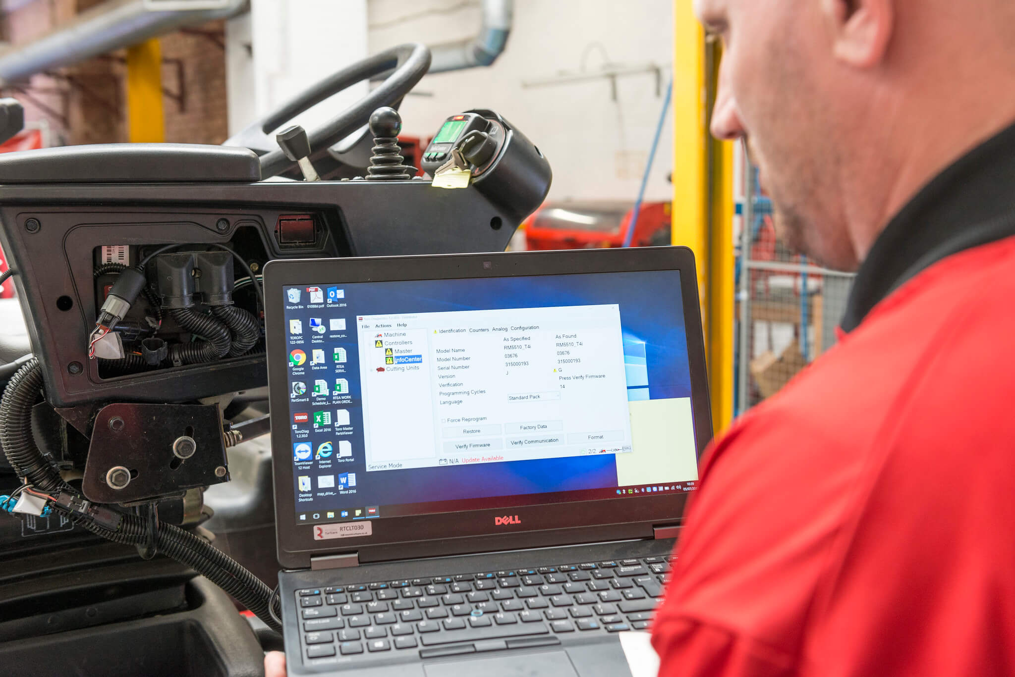 Turfcare mechanic looks at a laptop screen with InfoCentre software that is plugged into a Toro turfcare machine.