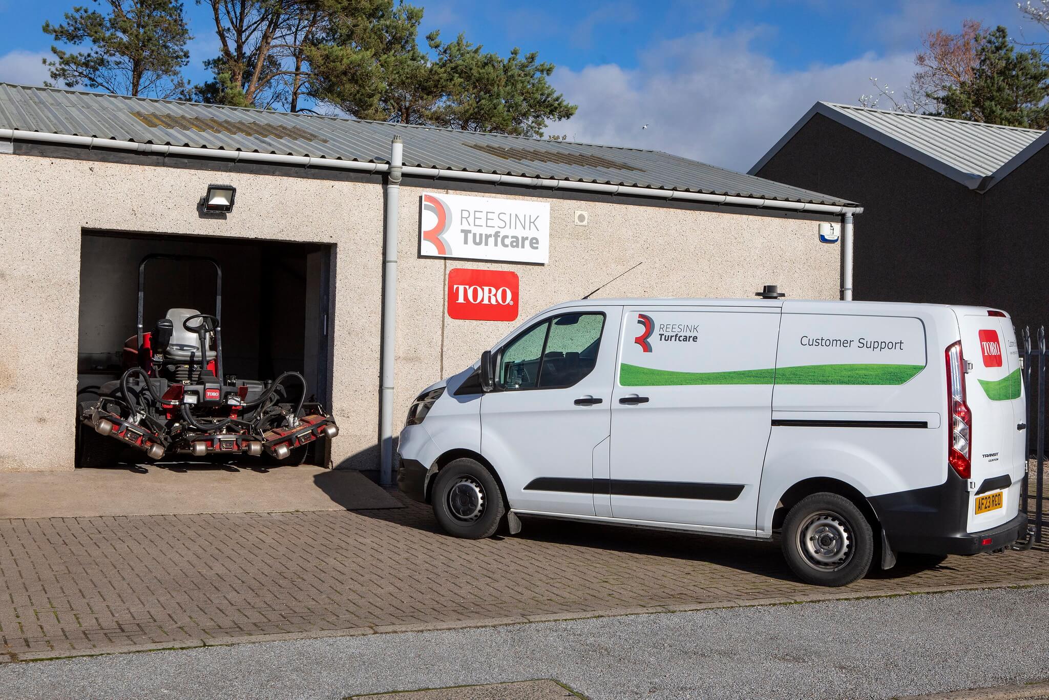 A Reesink Turfcare workshop with a Toro mower in the entrance and a customer support van parked outside.