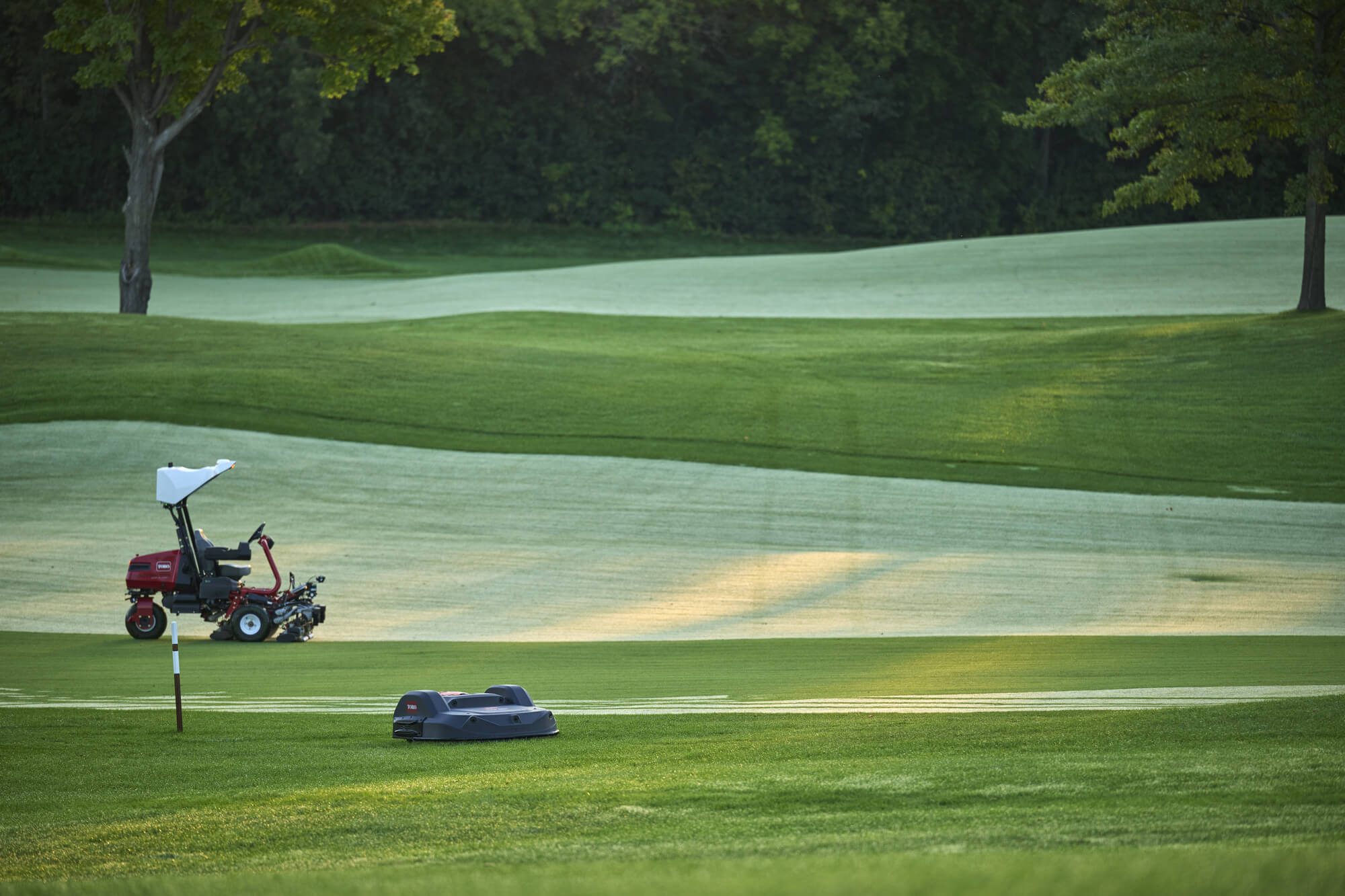 A Toro Greensmaster eTriFlex 3360 with GeoLink Mow and a Toro Turf Pro mower autonomously mowing a golf course.