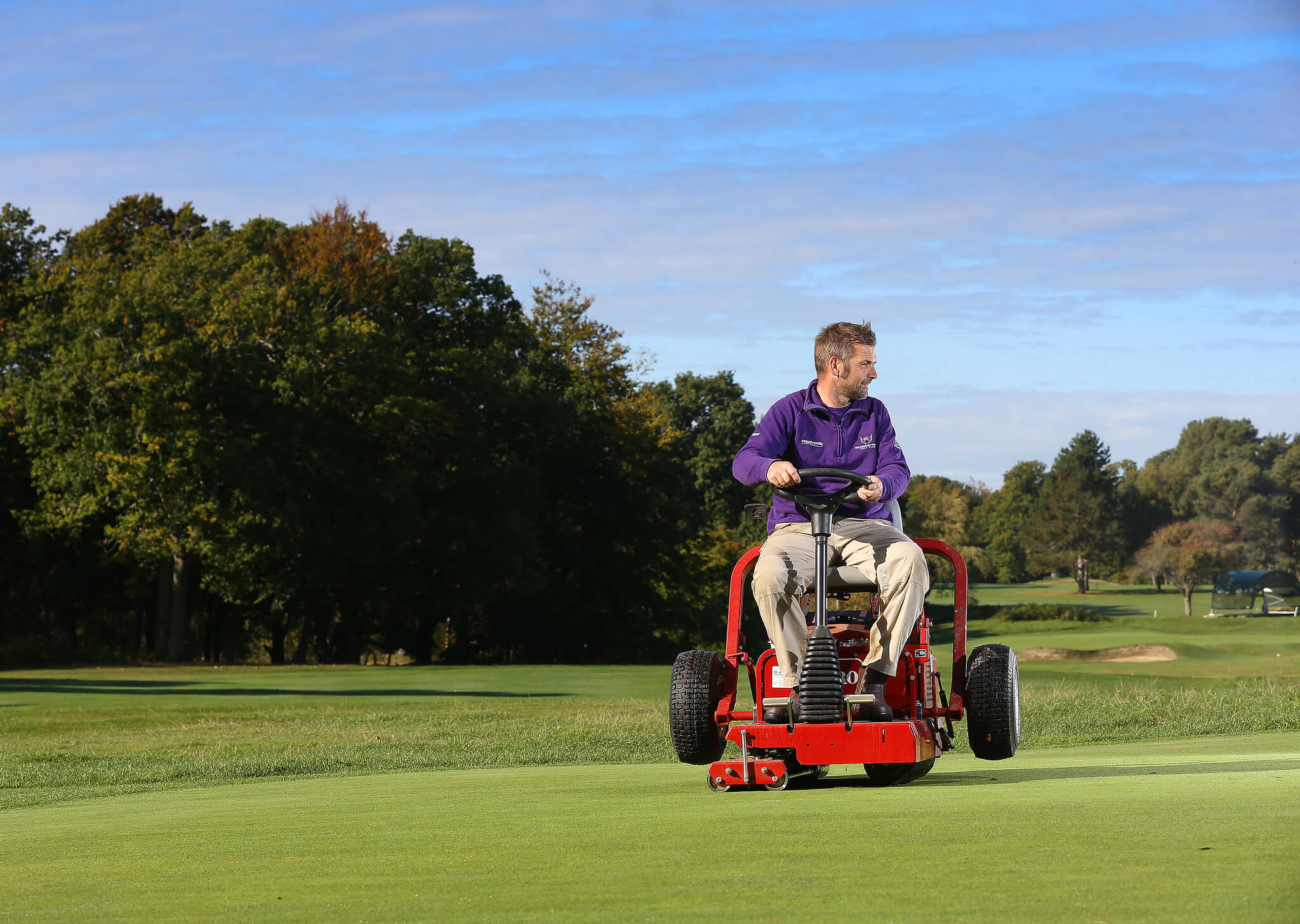 A greenkeeper rolls the golf course on a Toro GreensPro 1260.