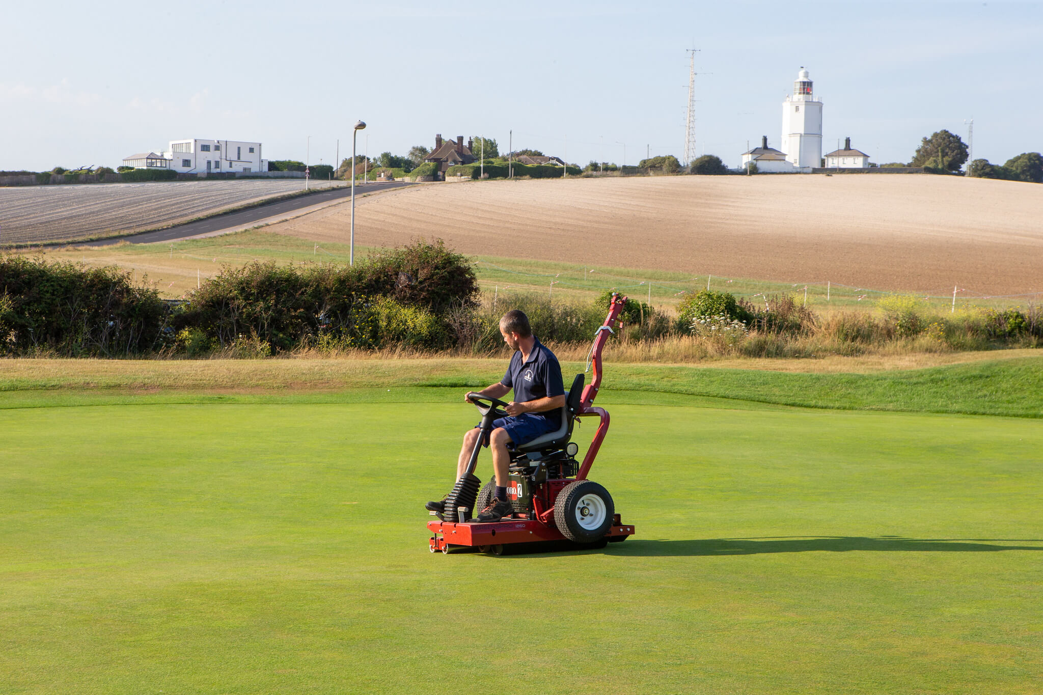 A greenkeeper uses a Toro GreensPro to roll the turf on a golf course.