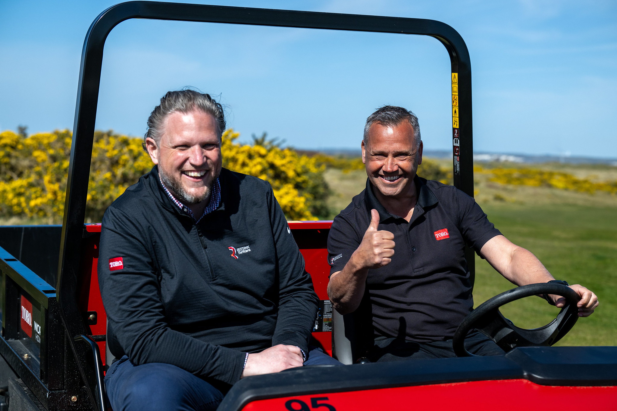 Reesink reps sit in a Toro Workman on a golf course.