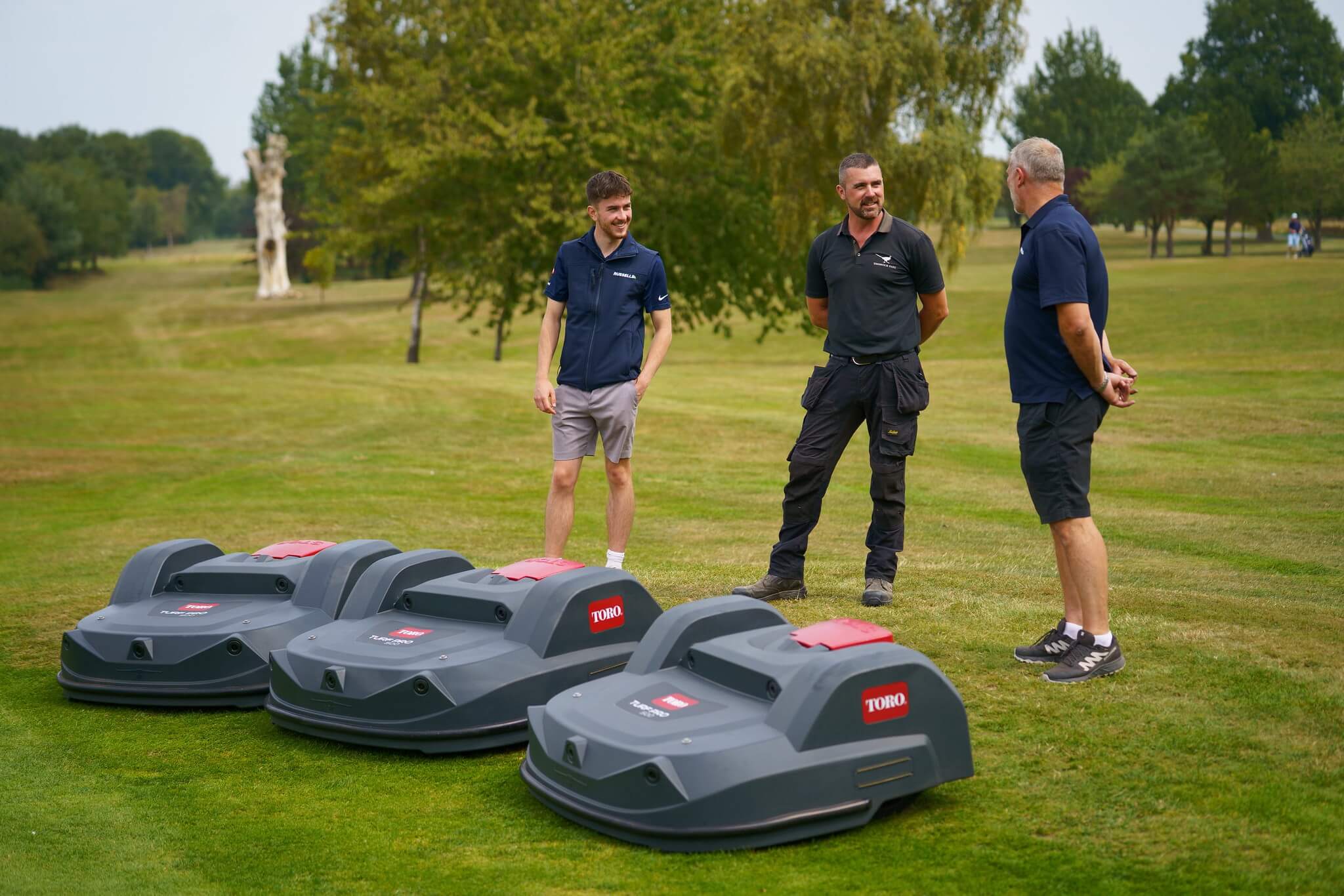 Three Toro Turf Pro 500 mowers are parked on Thonock Park course as three men stand next to them talking.