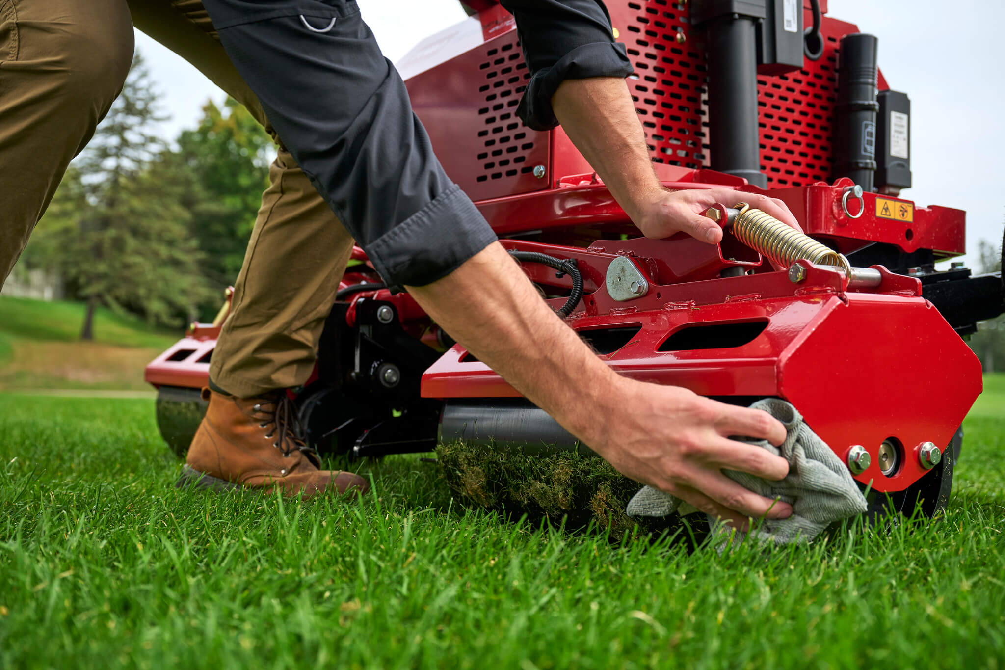 A greenkeeper wipes the rollers clean on Toro GreensPro turf roller.