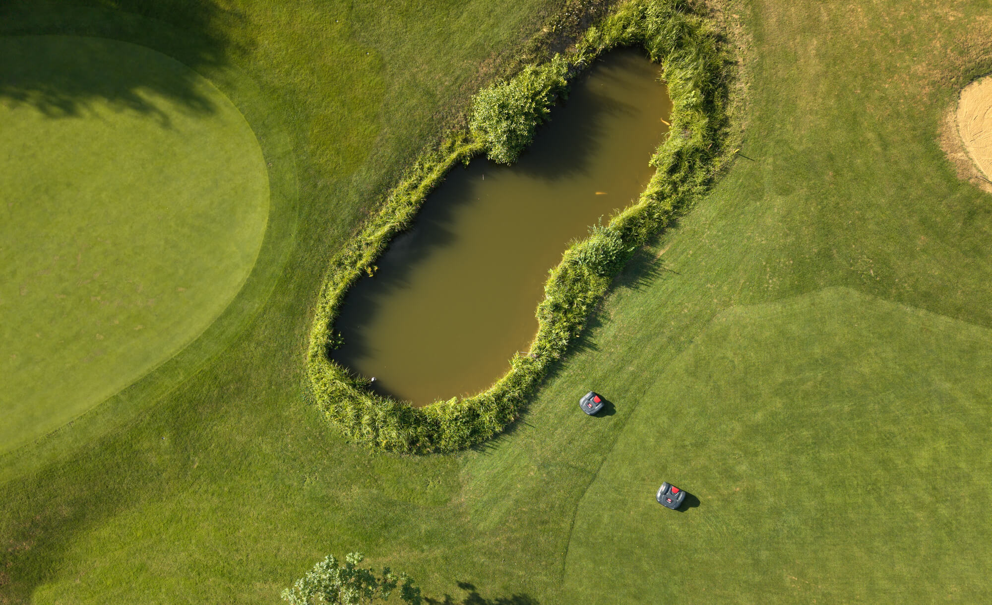 Aerial view of a golf course with two Toro Turf Pro 500 mowers autonomously mowing the turf.
