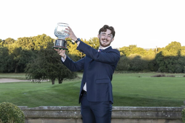 Daniel Parker, Young Student Greenkeeper of the Year 2024, holds his trophy in the air.