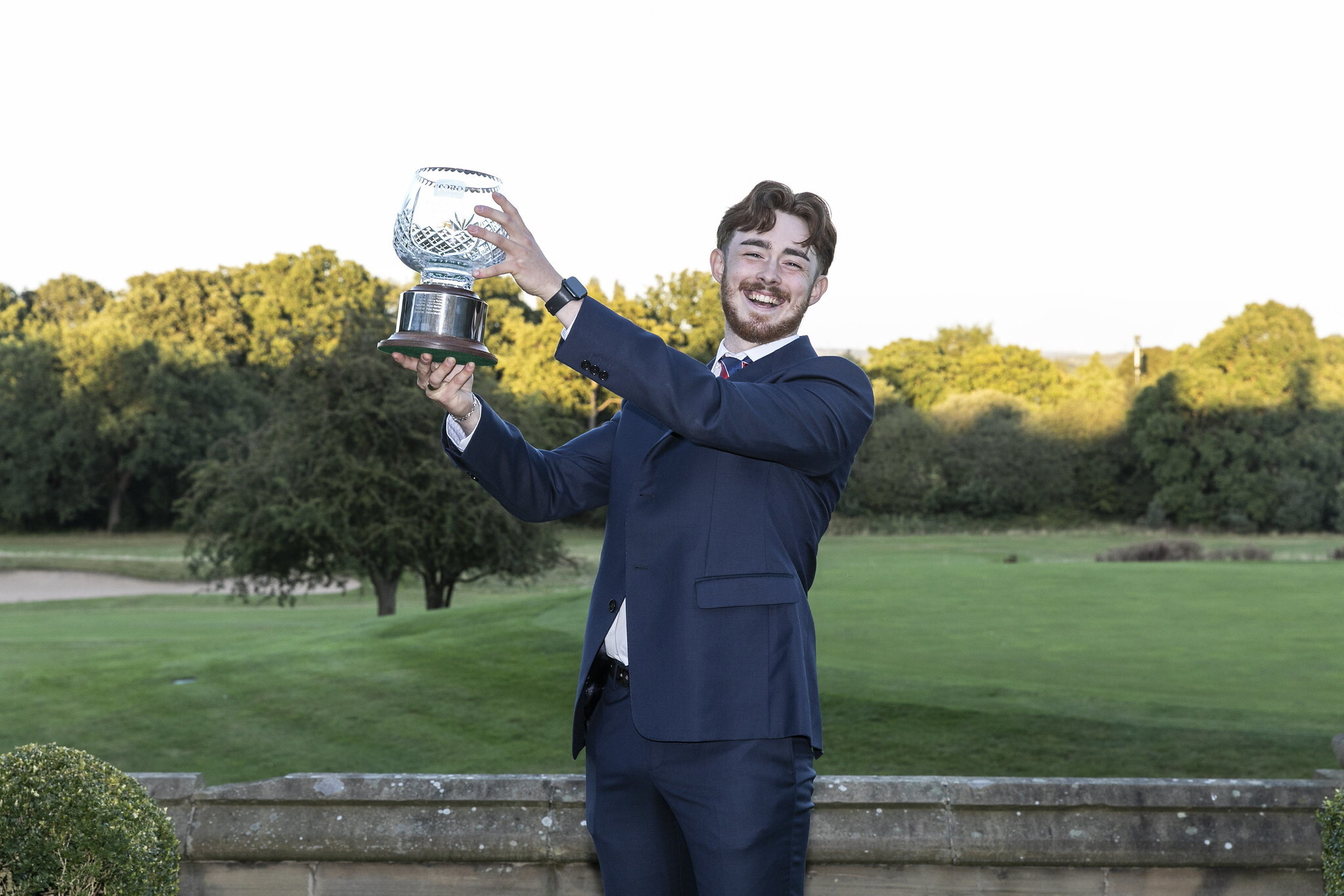 Daniel Parker, Young Student Greenkeeper of the Year 2024, holds his trophy in the air.