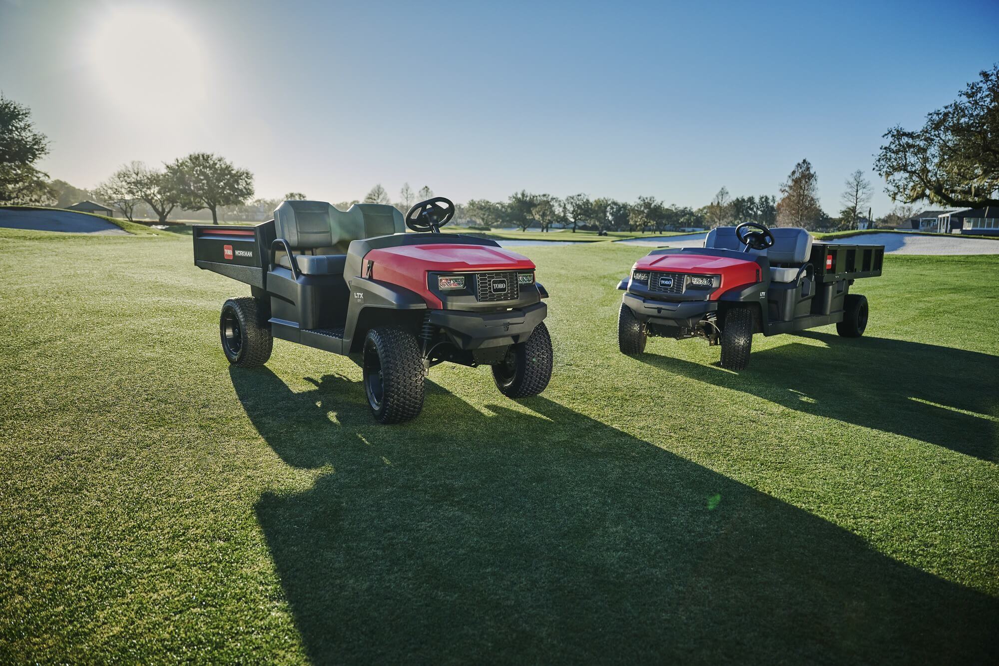 Two Toro Workman LTX utility vehicles on a golf course.