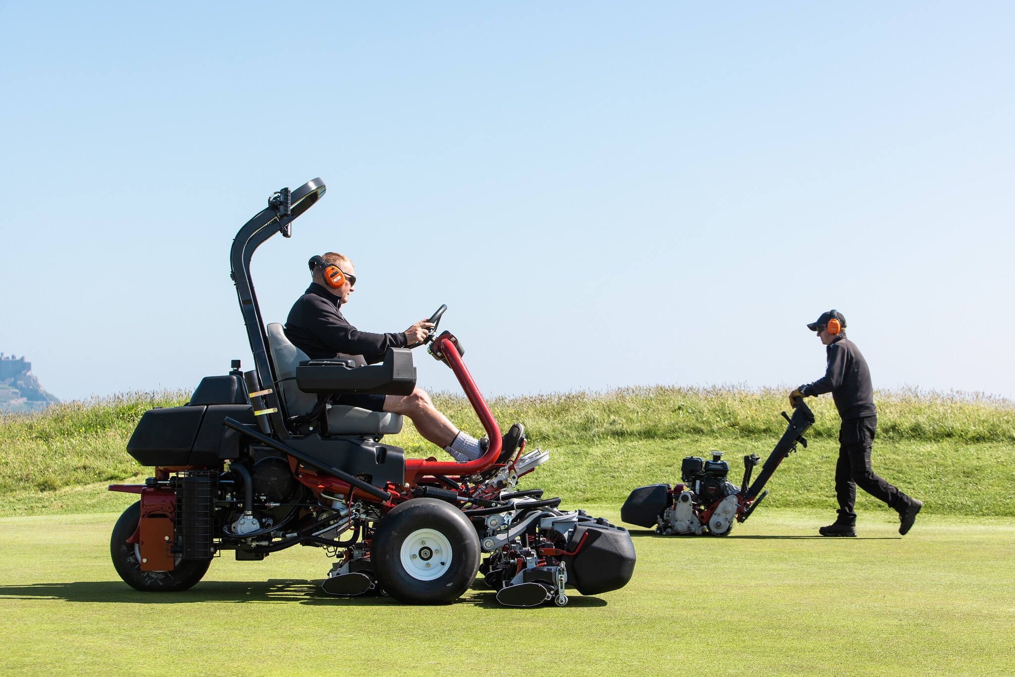 A Toro mower and pedestrian mower cutting a golf course.