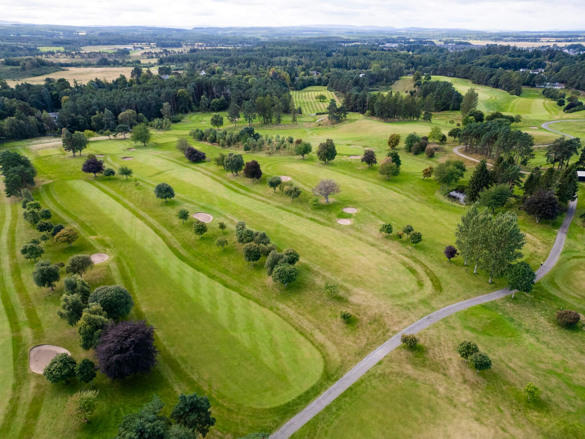 An aerial view of a golf course with patterned fairways.