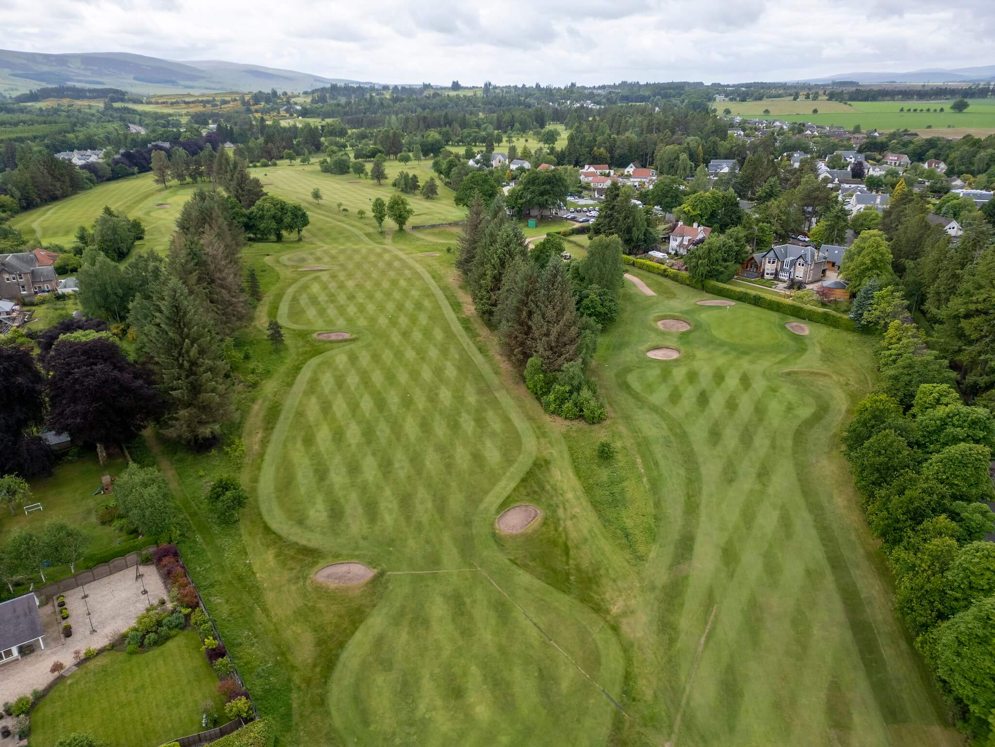 An aerial view of a golf course with diagonal or diamond fairway pattern.