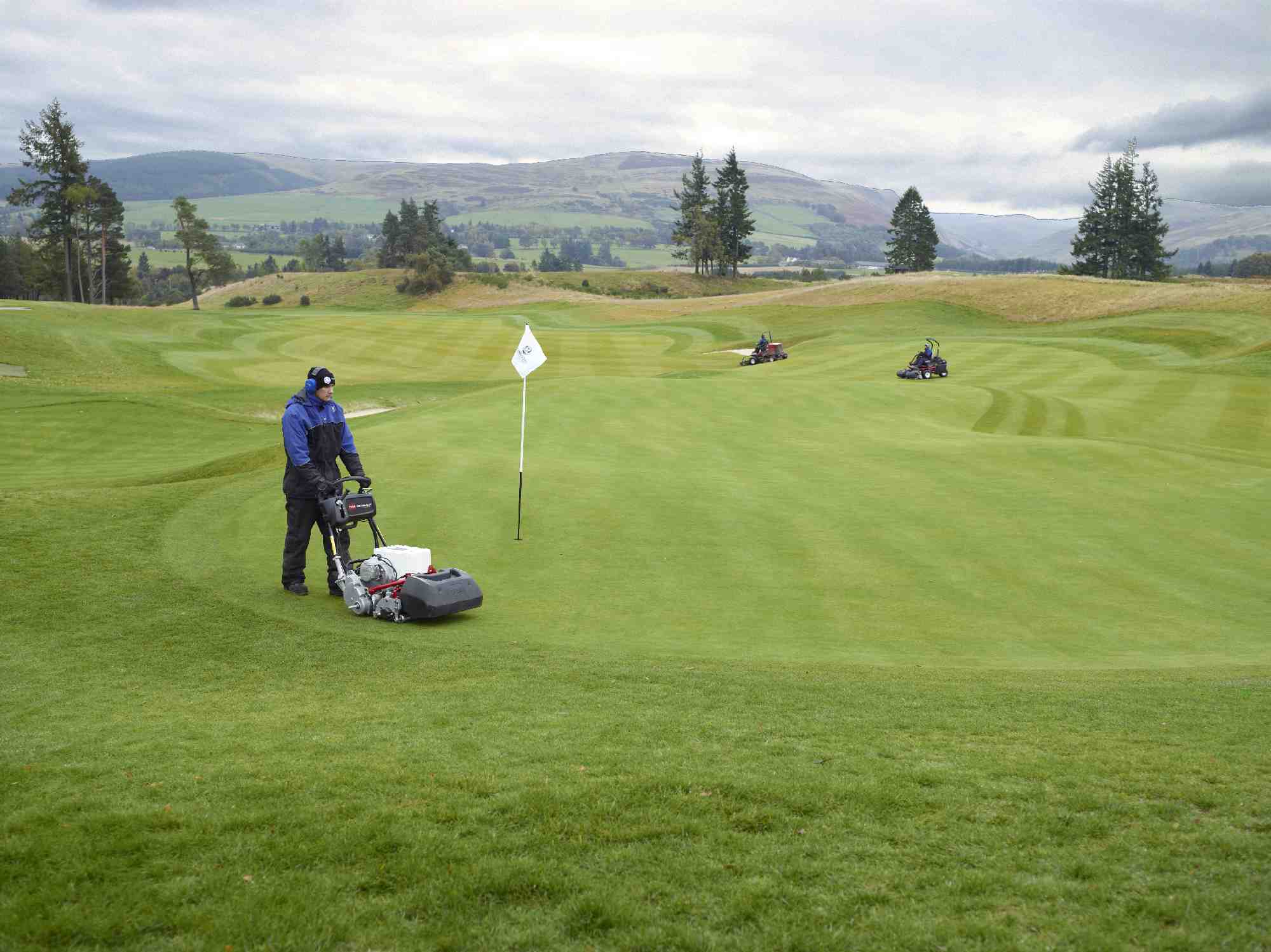 Greenkeepers mowing patterns into a golf course with Toro mowers.