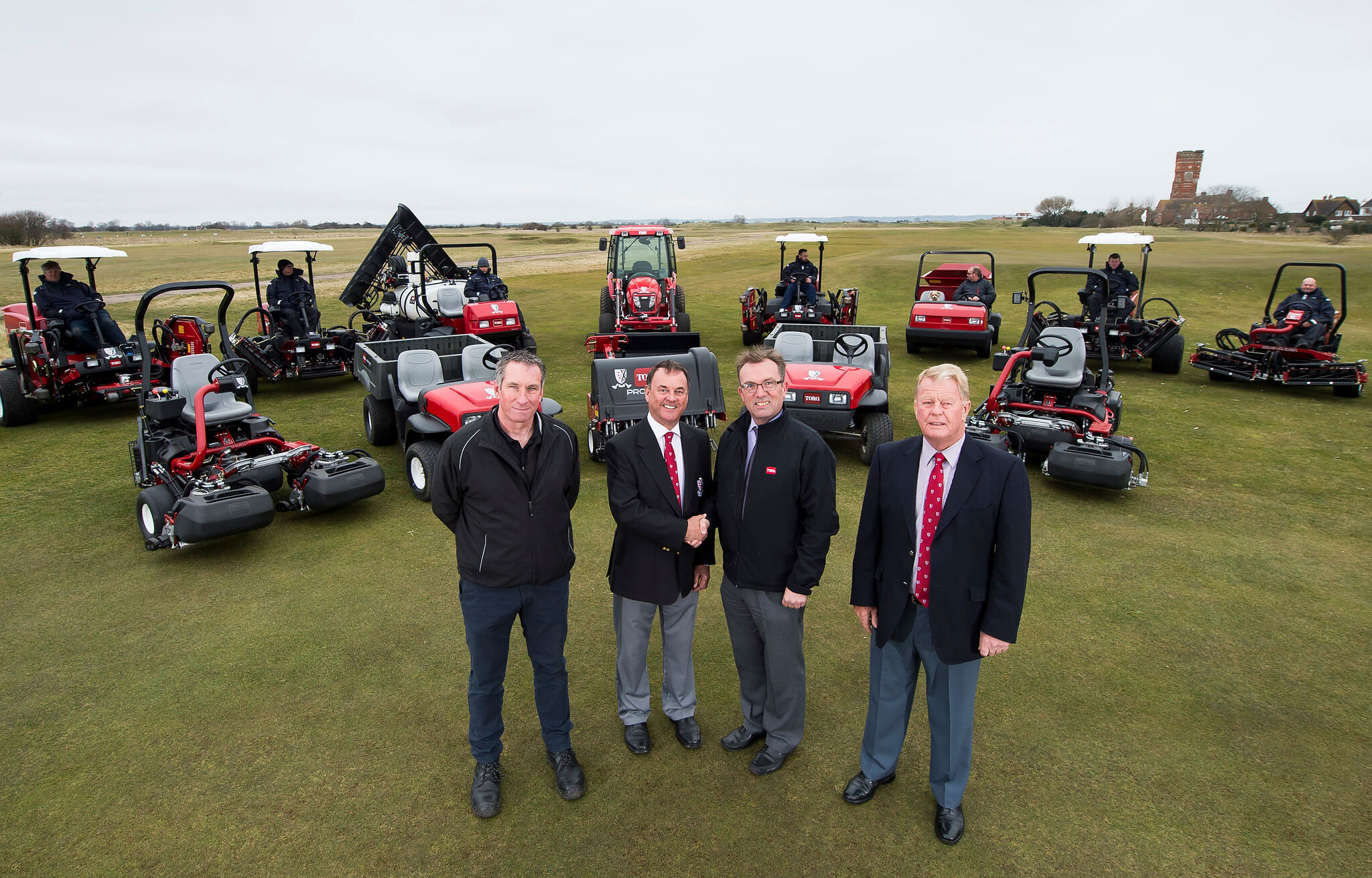 Reesink rep and Littlestone Golf Club reps shake hands in front of the new fleet of Toro mowers.