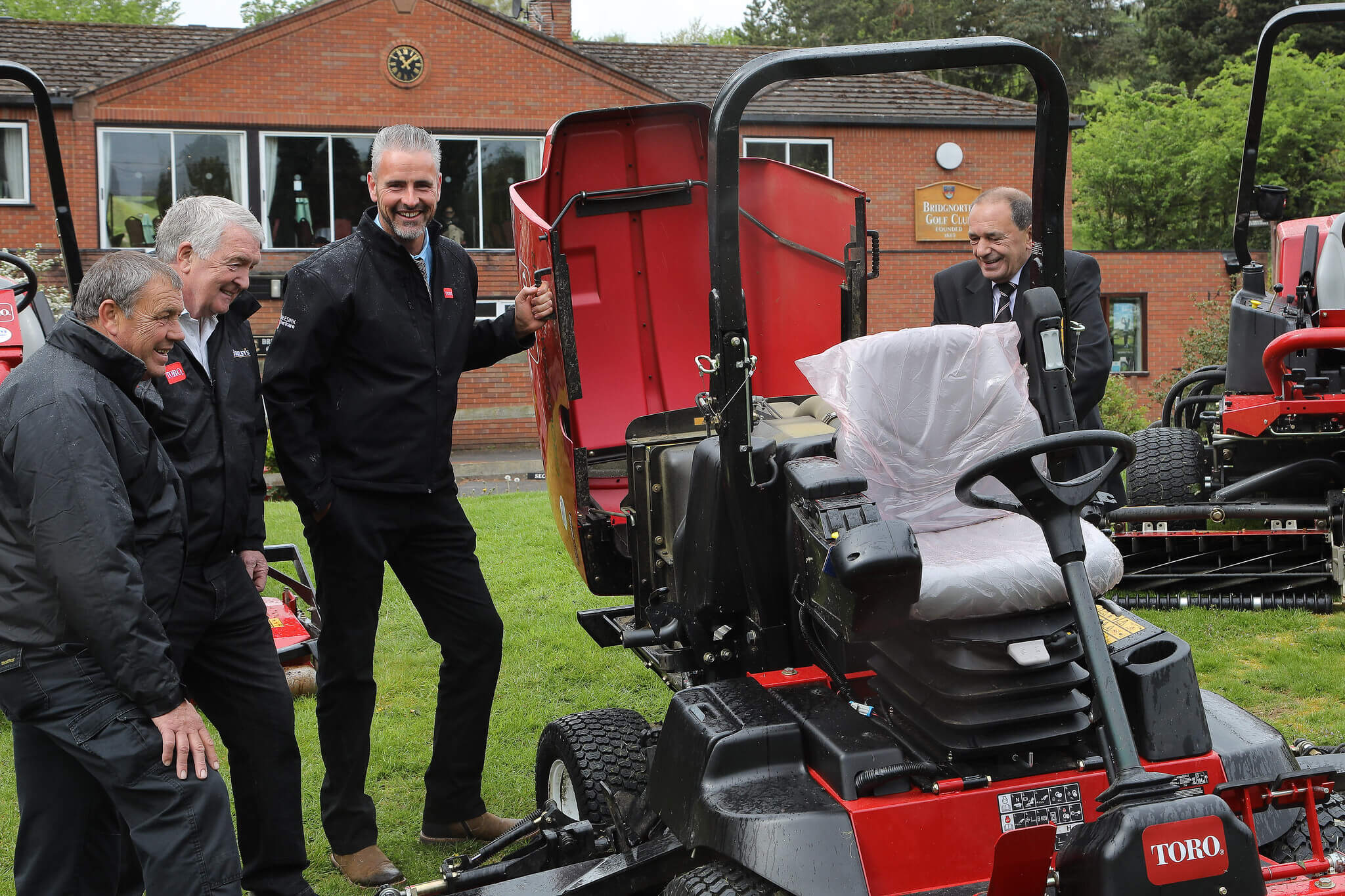 A Toro greensmower is opened and looked inside on a golf course.