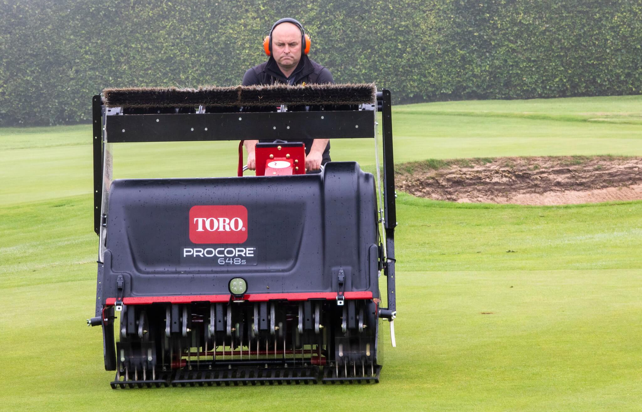A greenkeeper using a Toro ProCore 648s aerator.