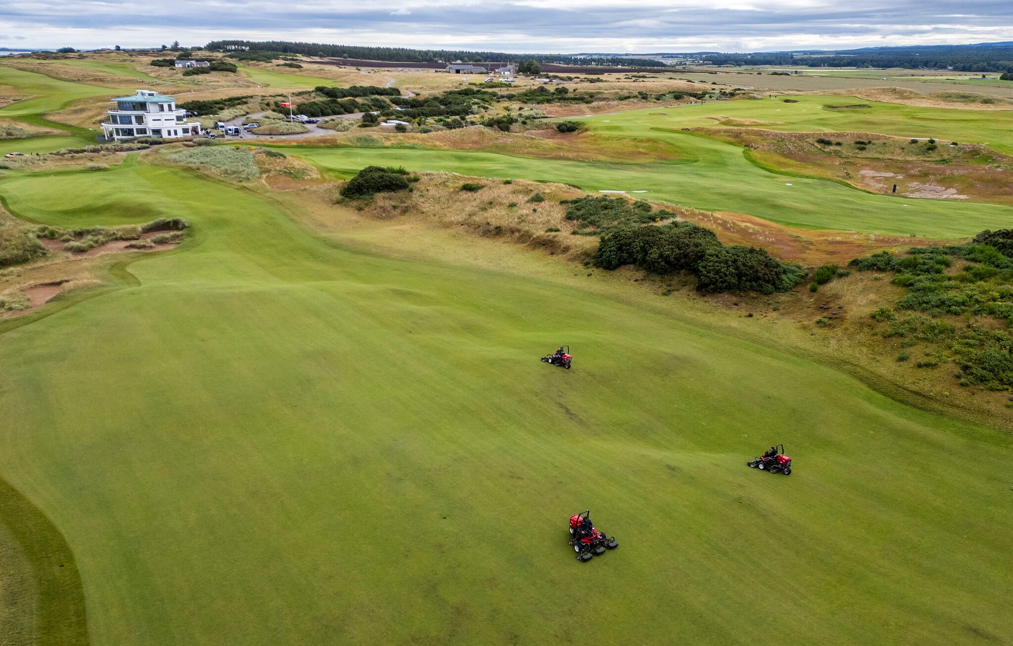 An aerial view of three Toro greens mowers working on a golf course.
