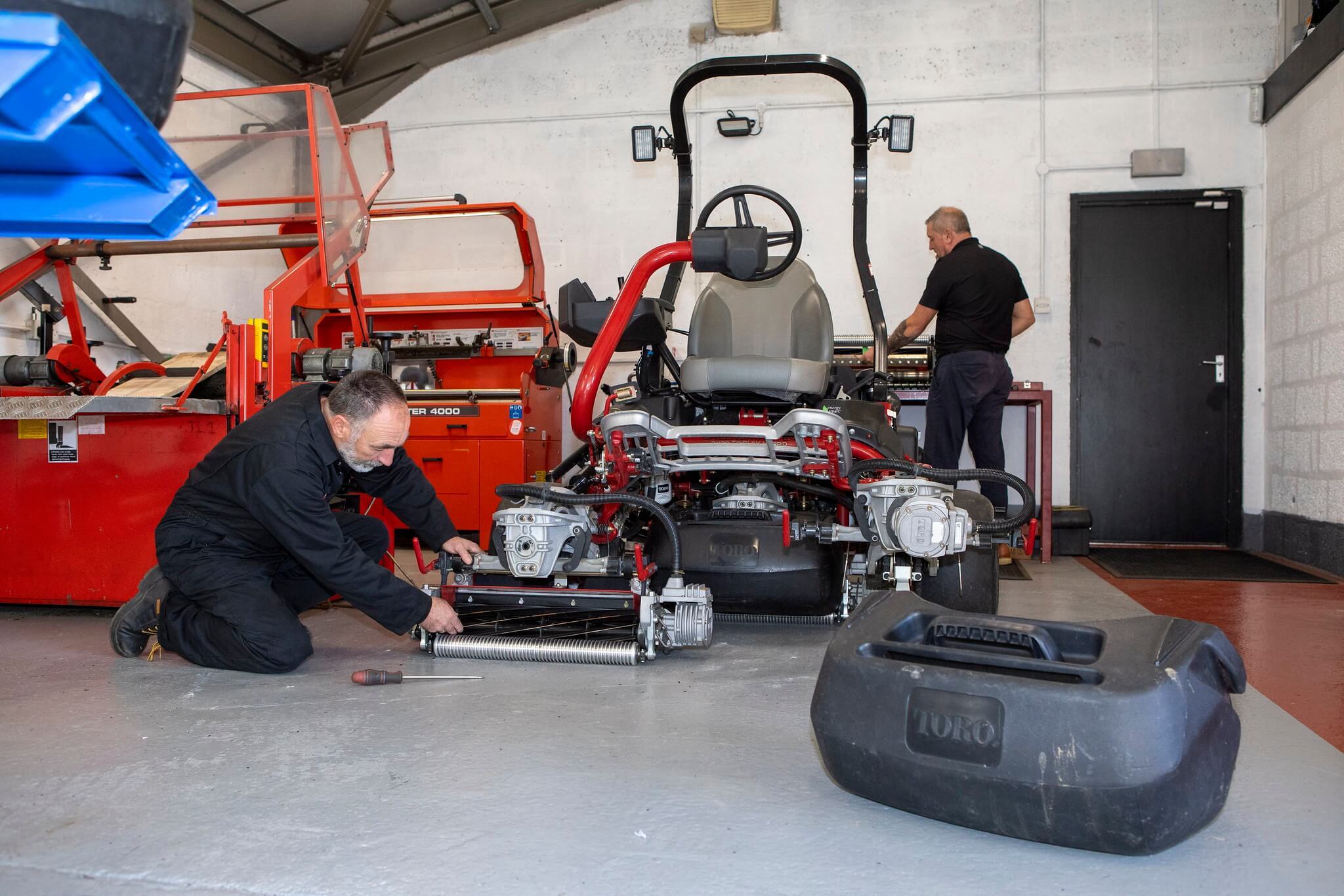 Turfcare mechanics in a workshop servicing a Toro mower.