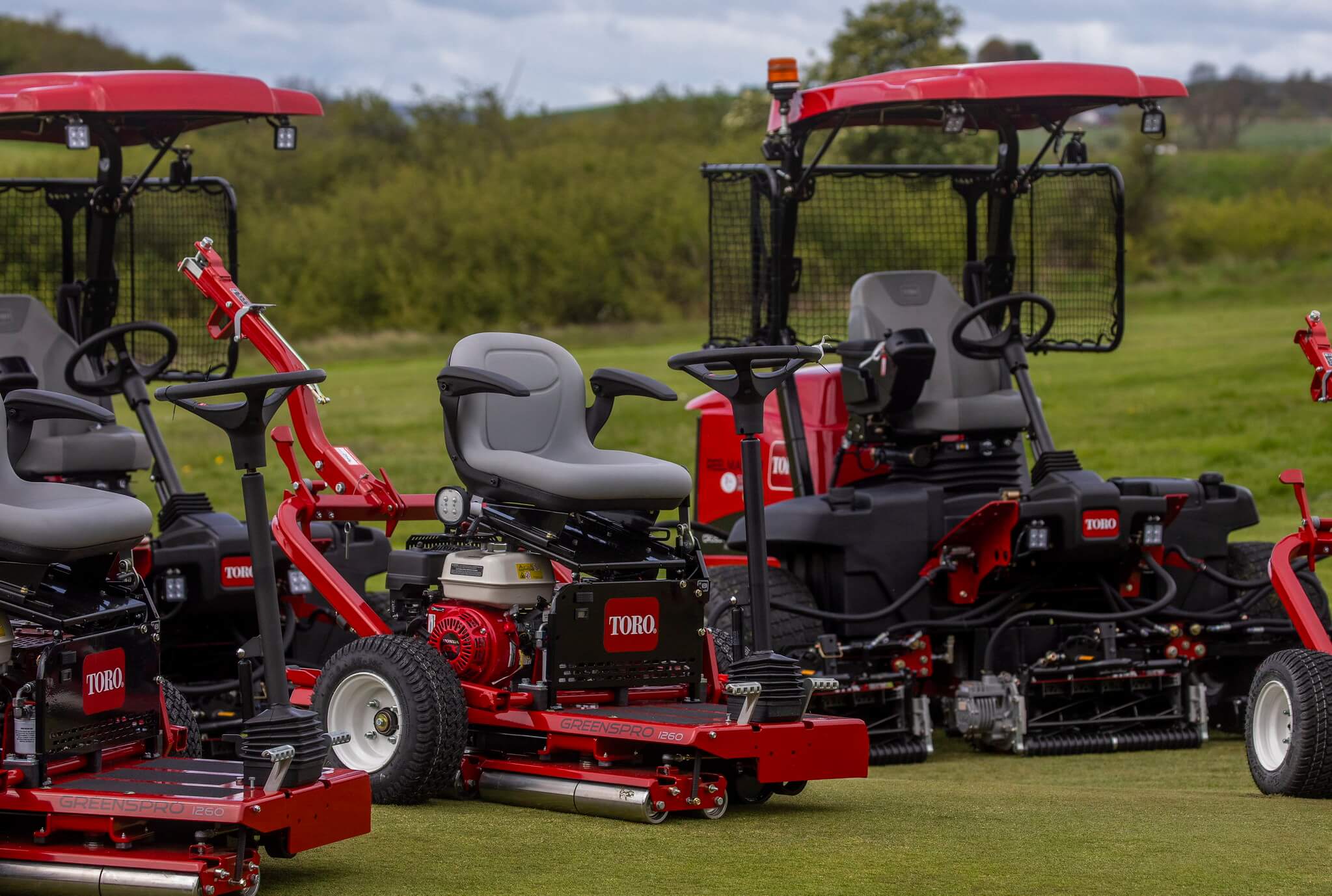 Three Toro greenkeeping machines on a golf course.