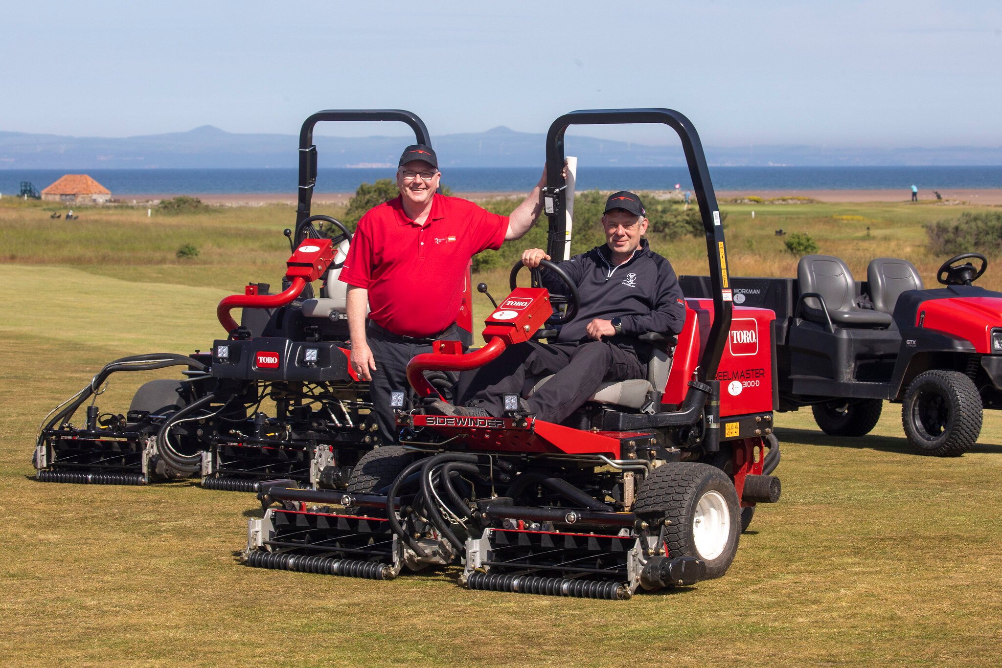 course manager seated on a Toro mower, reesink sales rep standing next to mower on the left. Other Toro mowers are in the background