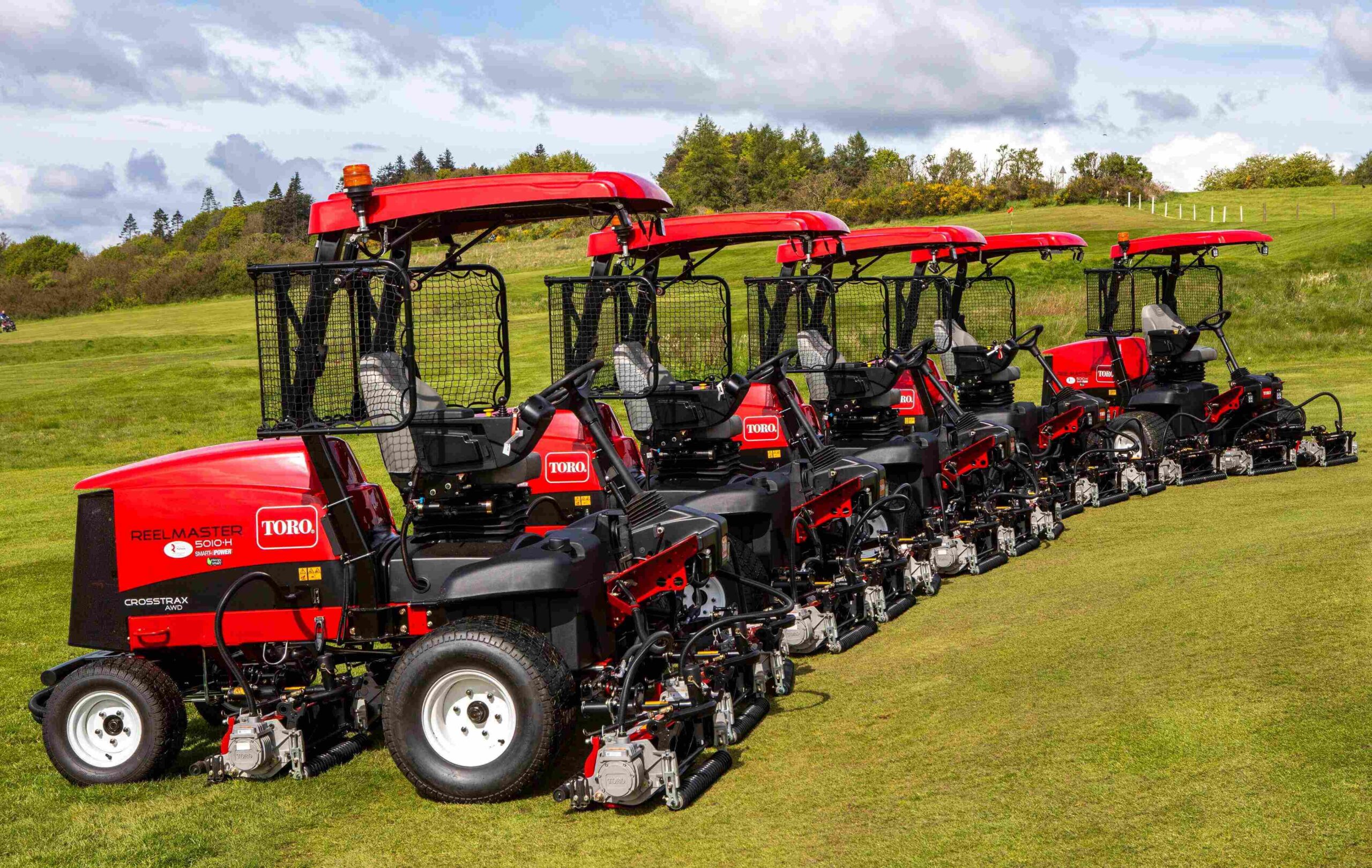 Five Toro Reelmaster 5010-H lined up side by side on a golf green.