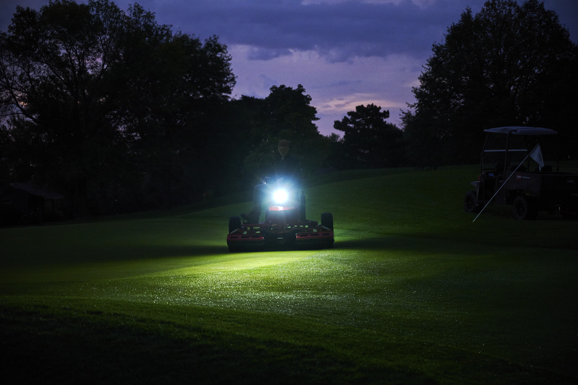 A Toro GreensPro e1700 all-electric greens roller with a light on rolling in the dark.