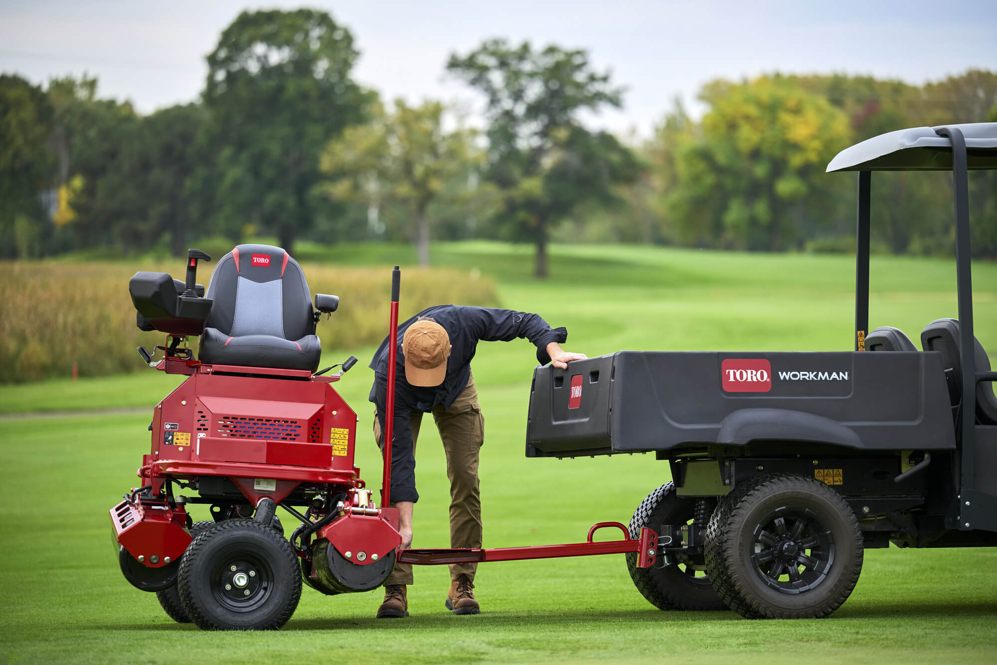 A Toro GreensPro e1700 all-electric greens roller being hitched to a Workman utility vehicle.