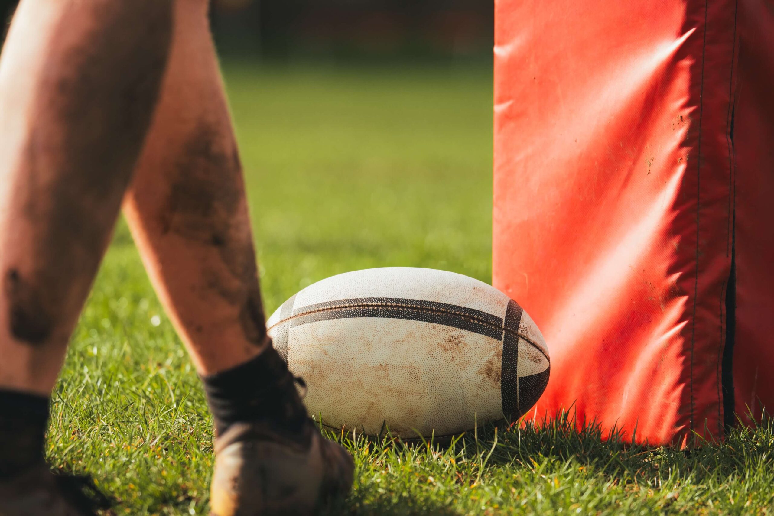 Rugby player on a sports pitch about to kick a ball.