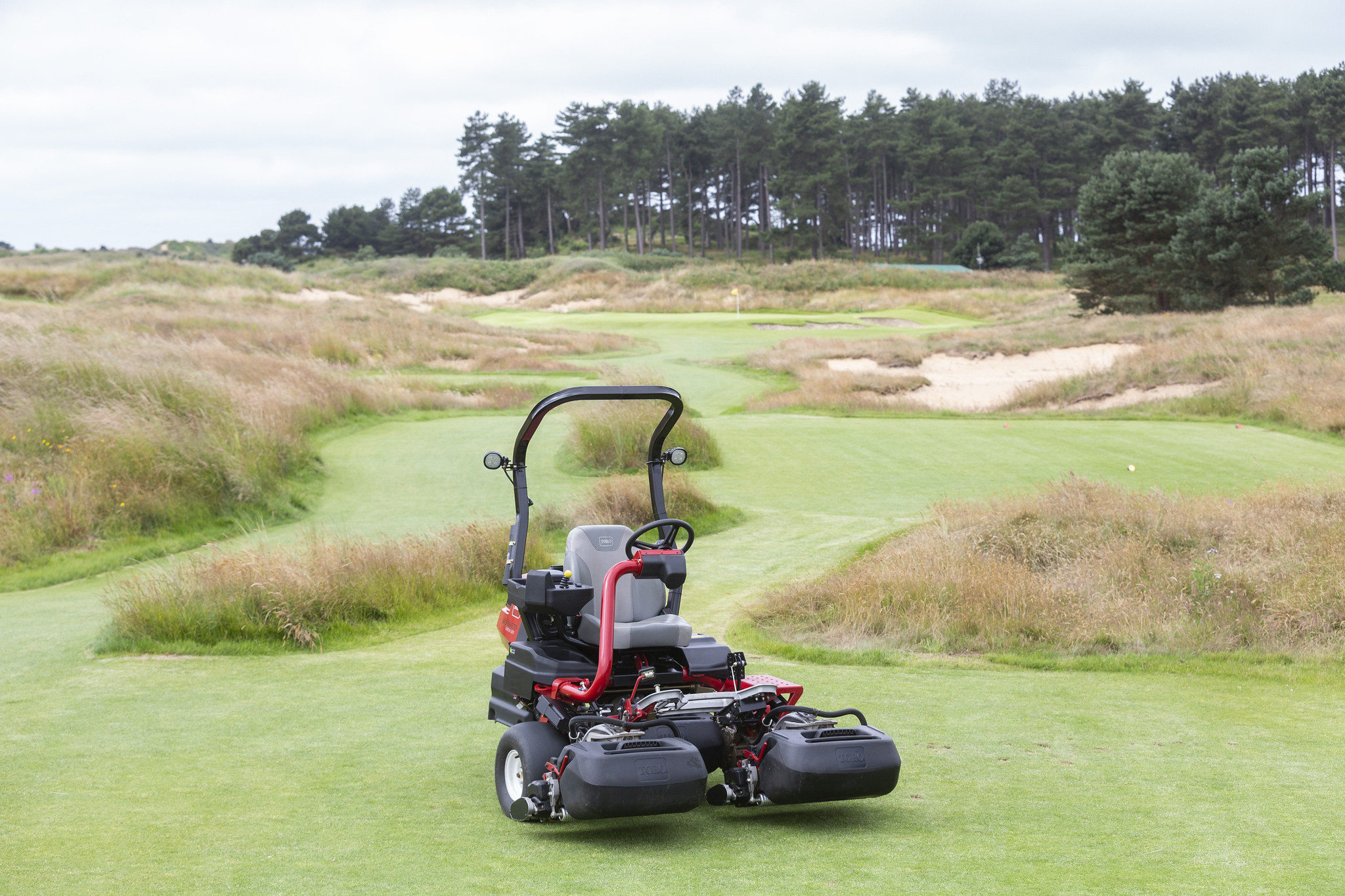 A Toro Greensmaster eTriFlex 3370 all-electric ride-on cylinder mower stationary on a golf course.
