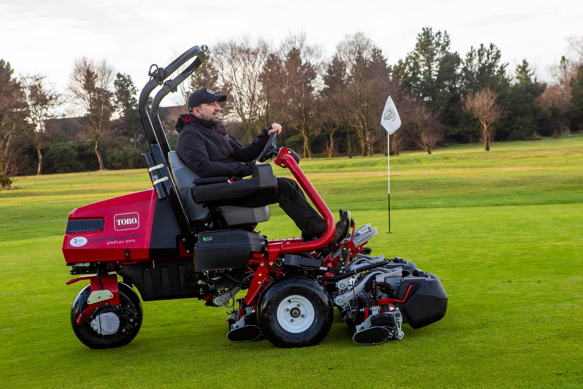 A greenkeeper mowing with a Toro Greensmaster eTriFlex 3370 all-electric ride-on cylinder mower.