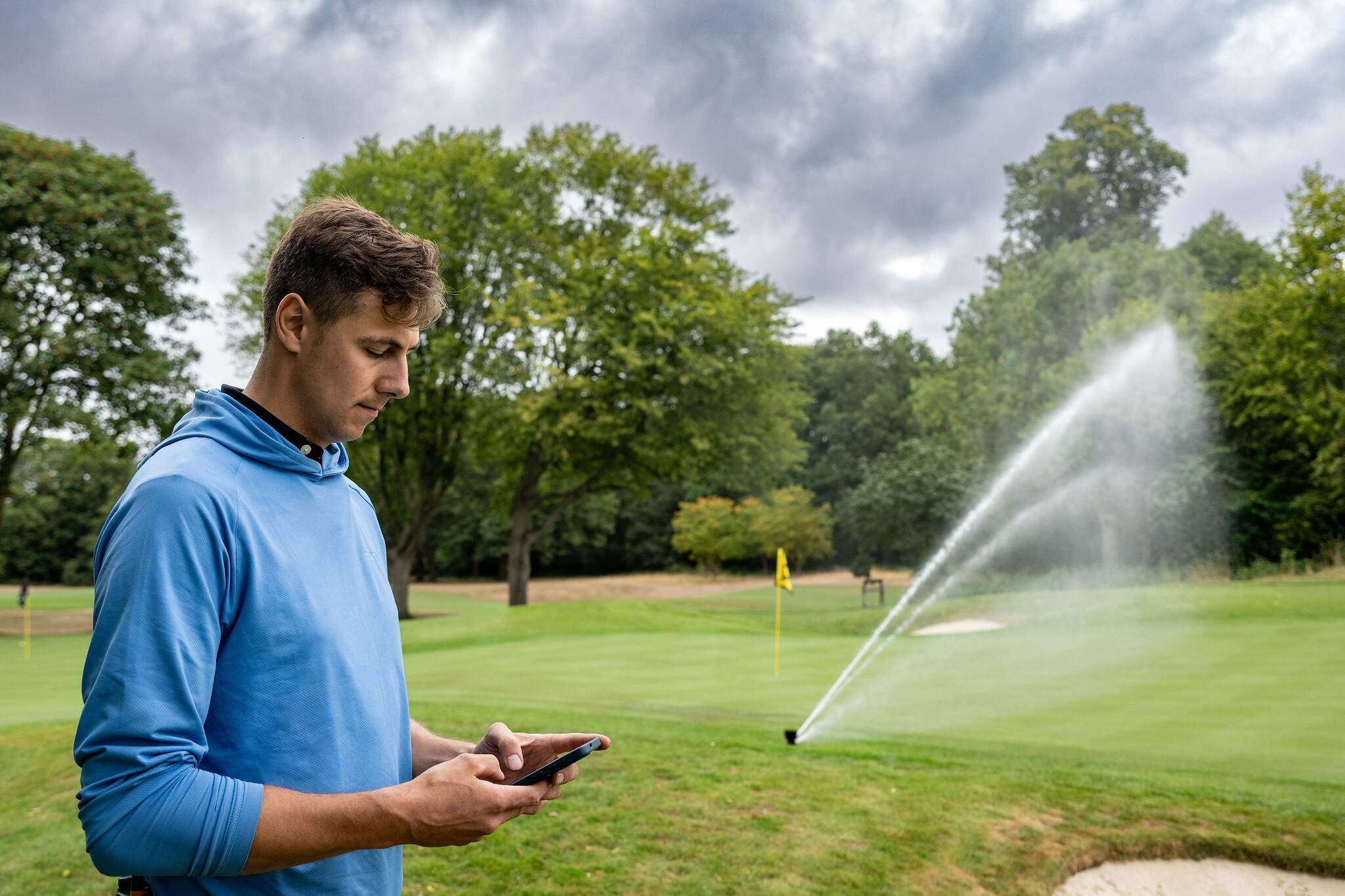 Sam Reid, Golf Course Manager at The Grove operating the Irrigation sprinklers with his mobile phone.