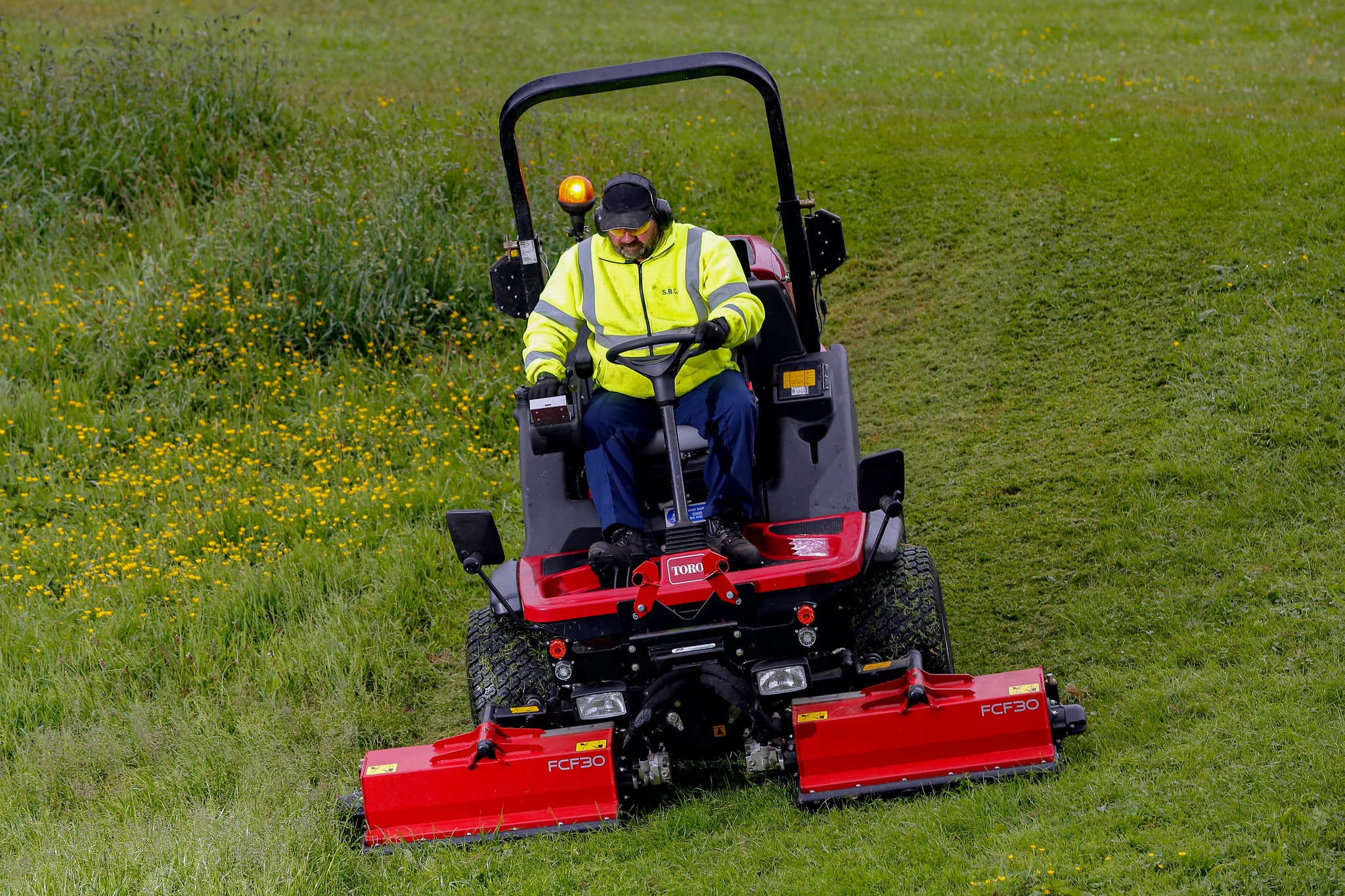 A Toro grounds mower cutting longer, rough grass.