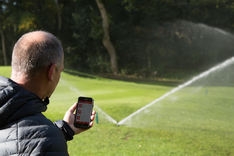 A groundsman controls his Toro irrigation sprinklers on his phone.