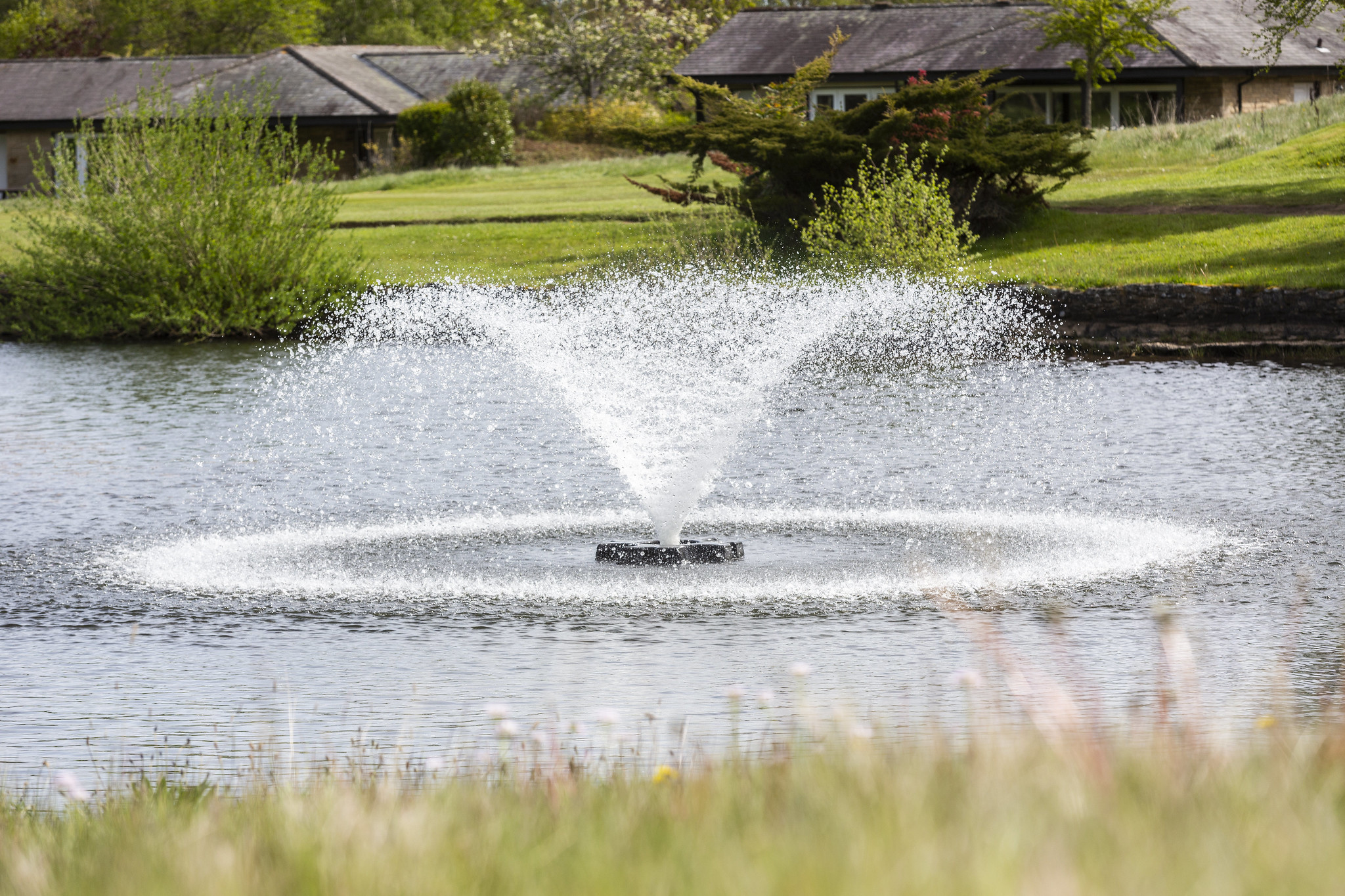 An Otterbine aerating fountain in a body of water in a housing estate.