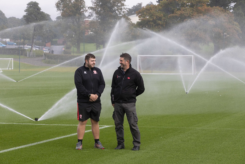 Middlesbrough FC's ground team benefits from the support of Pete Newton of Reesink Hydro-Scapes. Sprinklers are active on the pitch in the background.